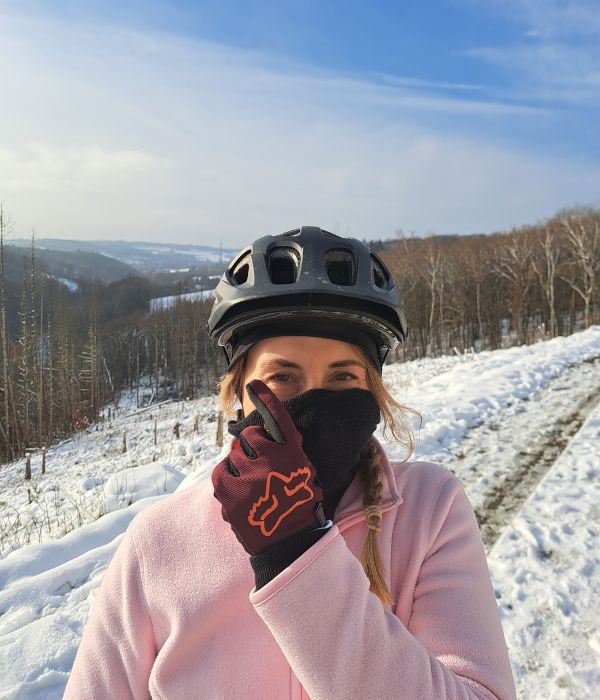 Mountainbike Fahrerin mit Schal vor dem Gesicht und Helm im Schnee