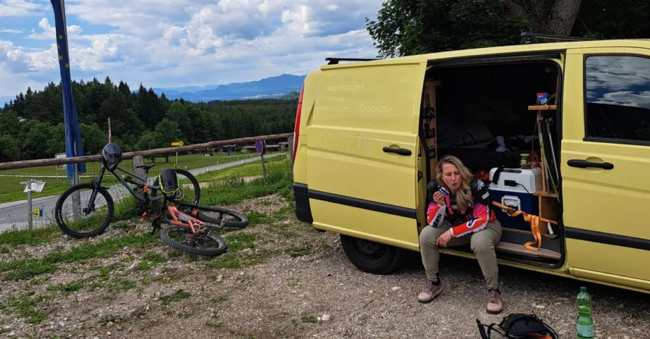Vanesssa sitzt nach nach einem Bikepark Tag im Van und isst für ihre Mountainbike Regeneration