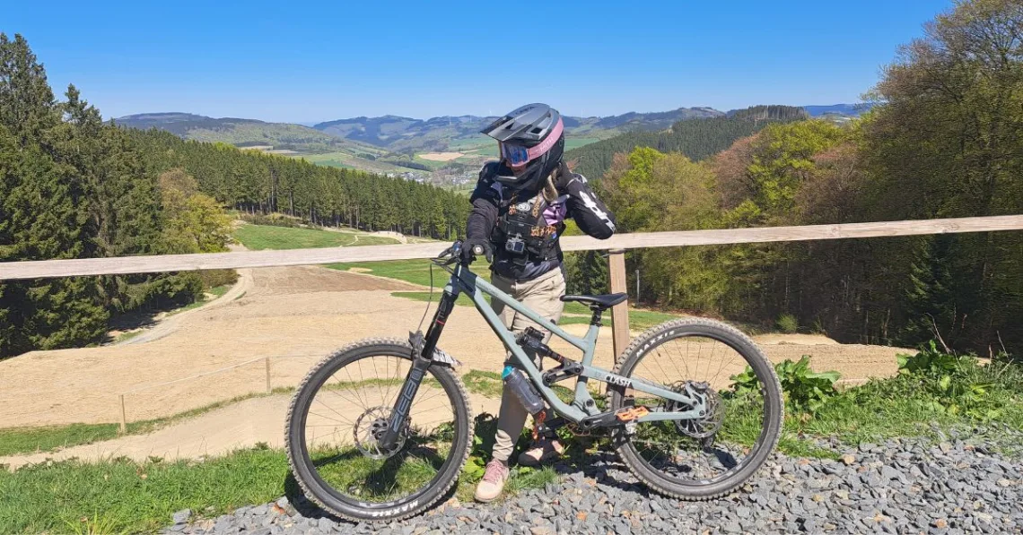 Vanessa steht im Green Hill Bikepark und trägt ihre Bikepark Kleidung